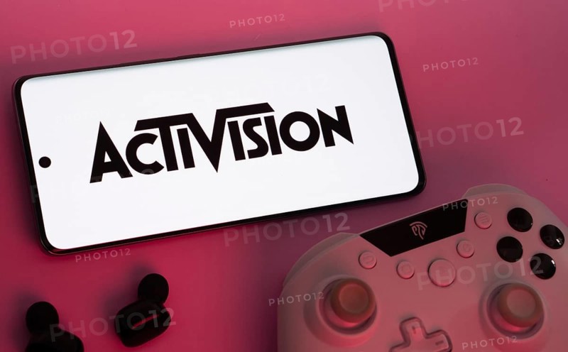 Dhaka, Bangladesh- 23 Sep 2025: Smartphone with Activision logo, game controller, and earbuds on a pink background