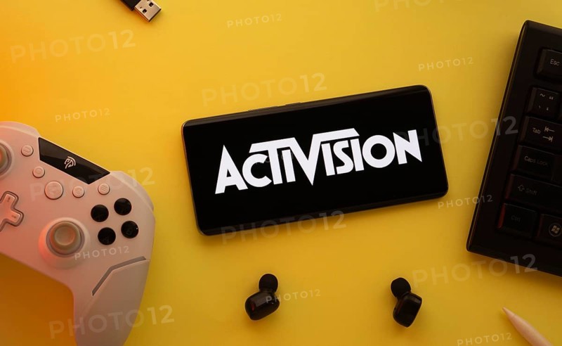 Dhaka, Bangladesh- 23 Sep 2025: Smartphone with Activision logo, game controller, and earbuds on a yellow background