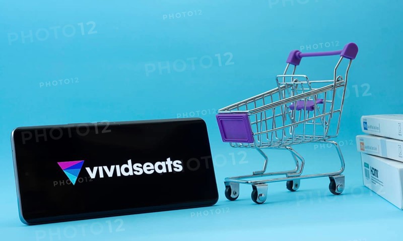 Dhaka, Bangladesh- 03 July 2025: Smartphone with VividSeats logo next to a small shopping cart and boxes against a blue background