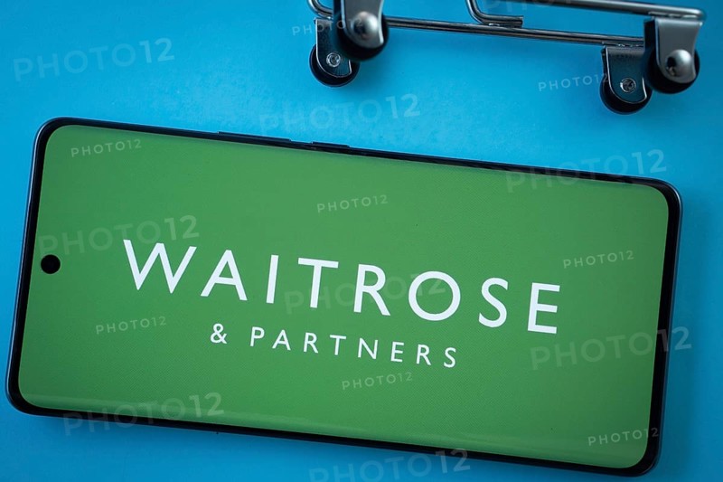 Dhaka, Bangladesh- 03 July 2025: Smartphone screen showing the Waitrose & Partners logo with shopping cart wheels on a blue background