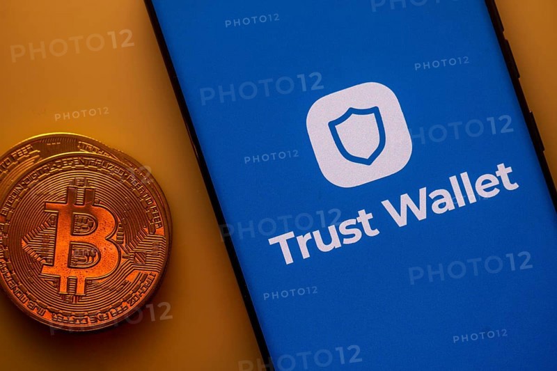 A Bitcoin coin next to a Trust Wallet logo on a blue background