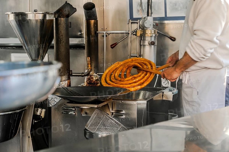 Man preparing tasty traditional churros in Seville, Spain