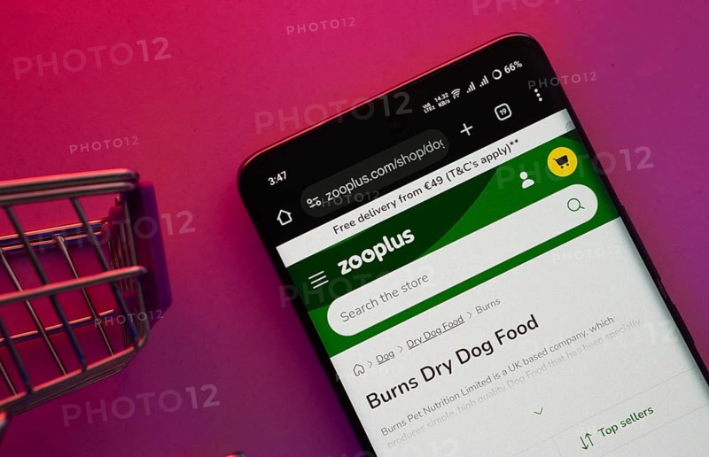 Dhaka, Bangladesh- 23 June 2025: A smartphone displaying the zooplus website with a shopping cart is shown on a vibrant background