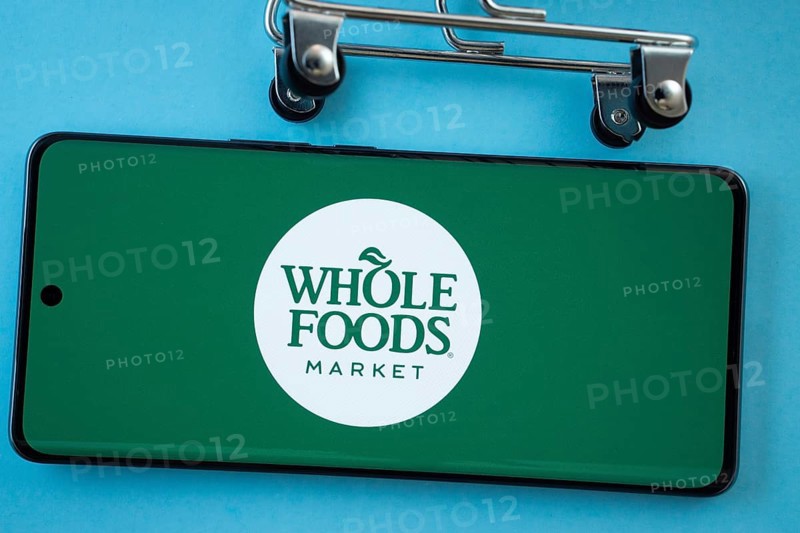 Dhaka, Bangladesh- 03 July 2025: Smartphone screen showing the Whole Foods Market logo with shopping cart wheels on a blue background