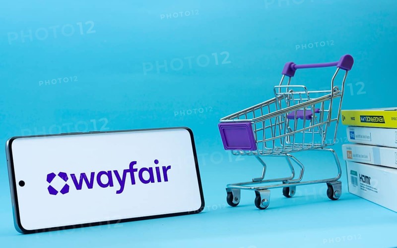 Dhaka, Bangladesh- 03 July 2025: Smartphone with Wayfair logo next to a small shopping cart and boxes against a blue background