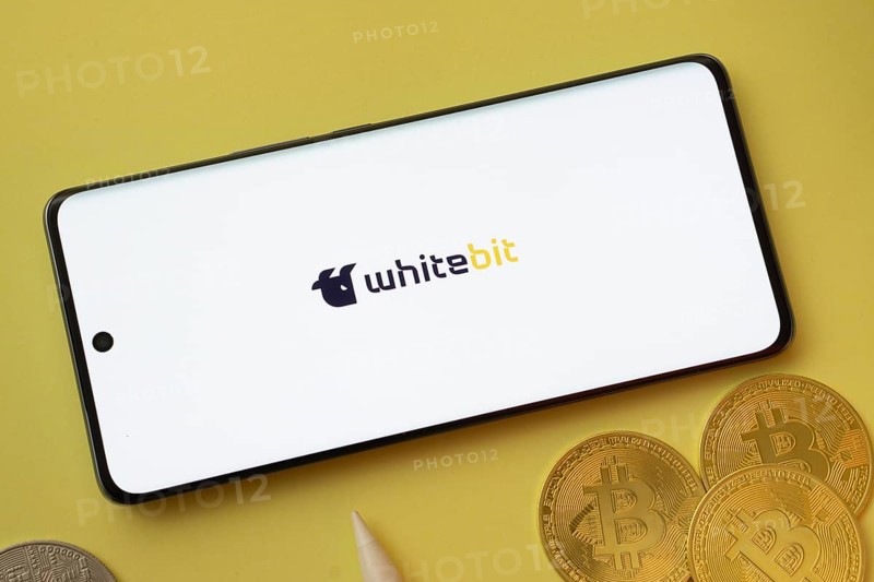 Dhaka, Bangladesh- 03 June 2025: whitebit logo on smartphone screen near Bitcoin coin and QR code on blue background