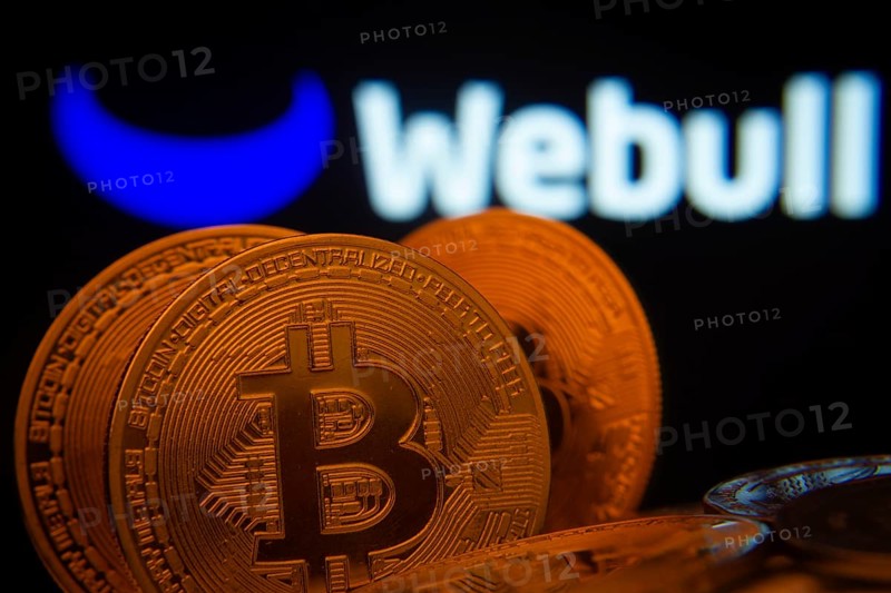 Dhaka, Bangladesh- 03 Sep 2025: Close-up of Bitcoin coins with the webull logo visible on a screen in the background