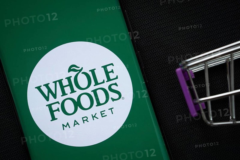 Dhaka, Bangladesh- 03 July 2025: A smartphone displaying the Whole Foods Market logo next to a miniature shopping cart on a background