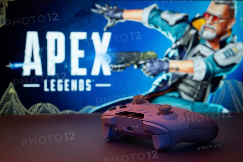 Dhaka, Bangladesh- 19 Sep 2025: A close-up of a white gamepad with the Apex Legends seen on screen in the background