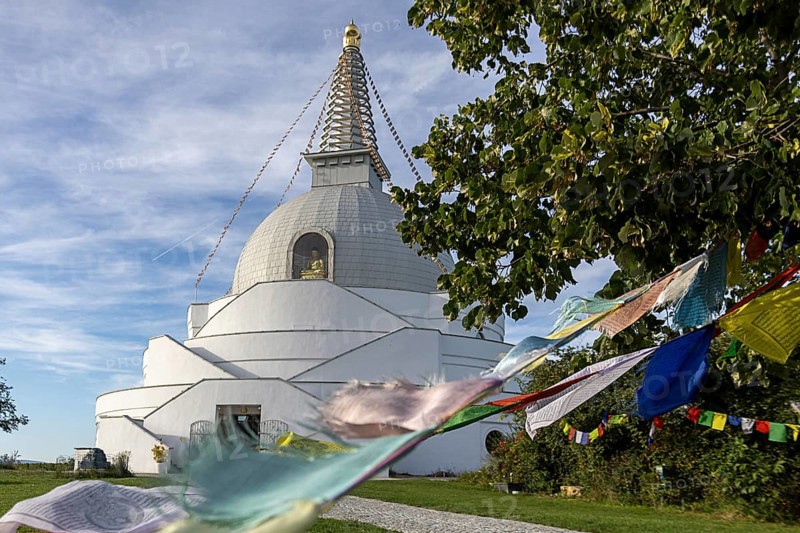White stupa with colourful prayer flags, peaceful surroundings, green foliage, blue sky, Stupa am Wagram Grafenwörth Weinviertel Lower Austria Austria