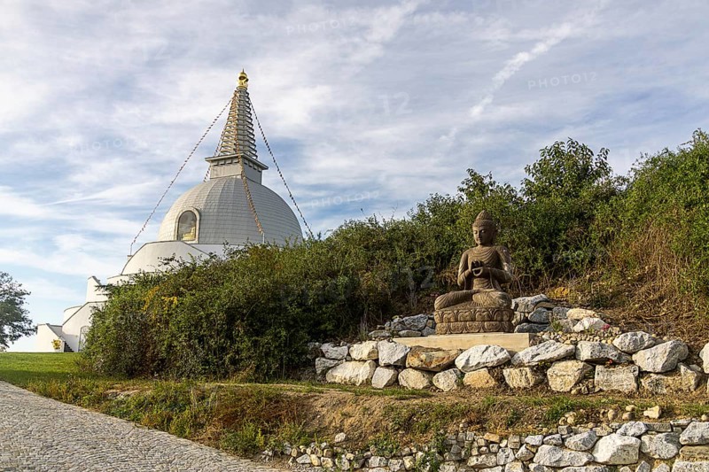 Buddha statue sitting on stones next to a pagoda in a green landscape, Stupa am Wagram Grafenwörth Weinviertel Lower Austria Austria