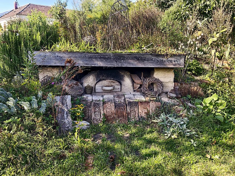 An old stone oven embedded in nature with surrounding plants and a rustic atmosphere, Weinviertel Lower Austria Austria