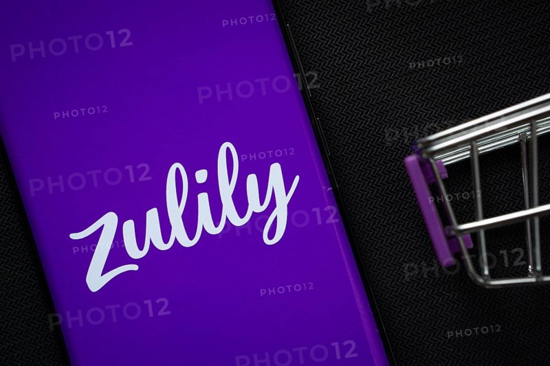 Dhaka, Bangladesh- 03 July 2025: A smartphone displaying the Zulily logo next to a miniature shopping cart on a background