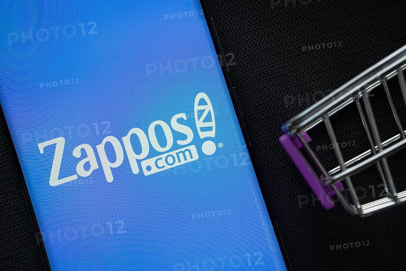 Dhaka, Bangladesh- 03 July 2025: A smartphone displaying the Zappos logo next to a miniature shopping cart on a background
