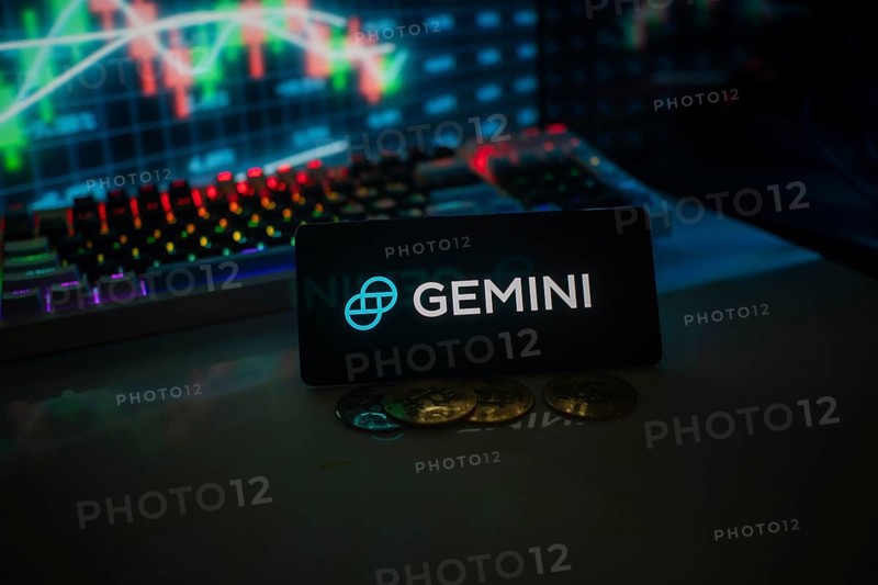 GEMINI logo set against market charts and coins, illuminated by colorful neon lights