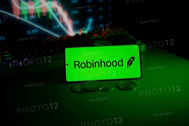 Robinhood logo on a phone with coins, set against a stock chart with green neon glow