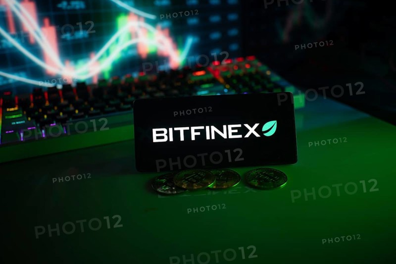 Bitfinex screen with coins in front of a stock chart illuminated by green neon lights