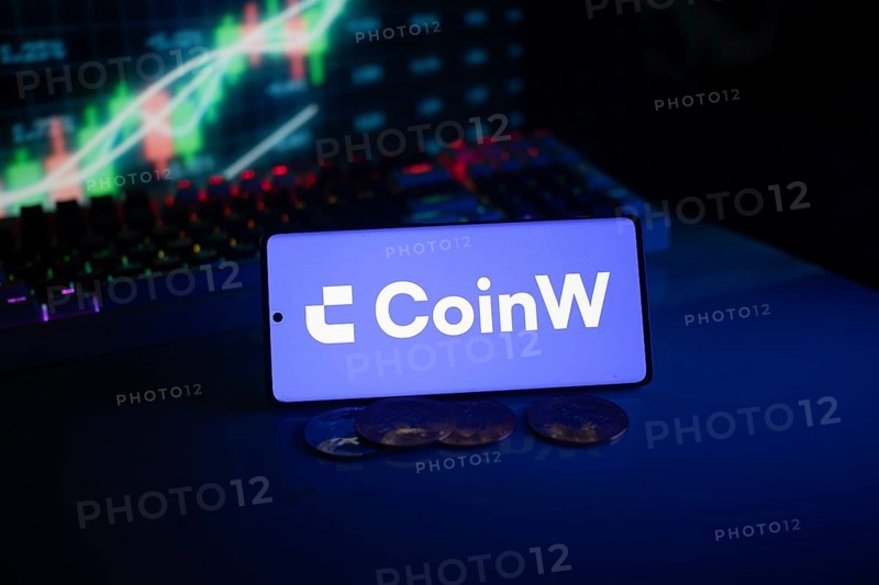 CoinW screen with coins, set in front of a neon-illuminated stock chart in blue