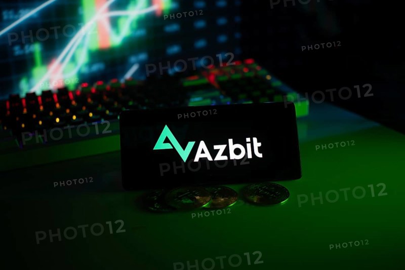Azbit logo on phone, displayed with coins and stock chart, emphasizing finance and technology