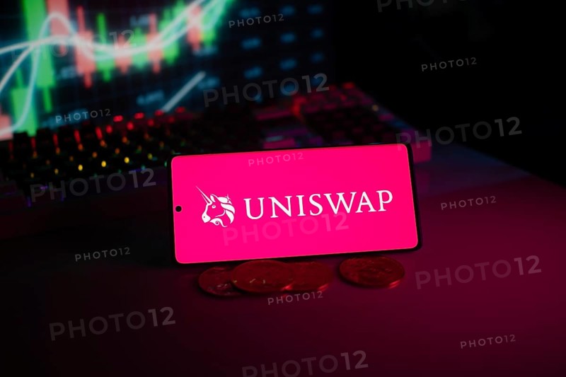 Uniswap logo on smartphone with coins and stock chart, highlighting digital finance and trading