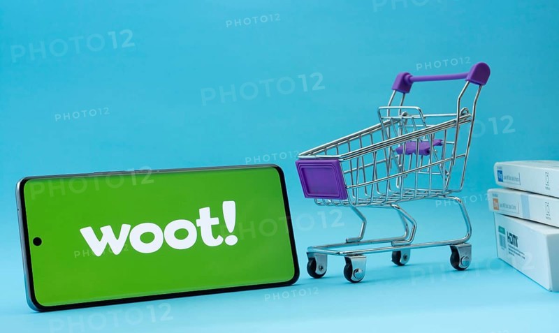 Dhaka, Bangladesh- 03 July 2025: Smartphone with Woot logo next to a small shopping cart and boxes against a blue background