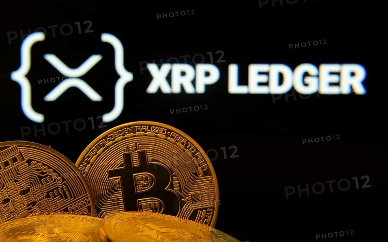 Dhaka, Bangladesh- 27 July 2025: Close-up of Bitcoin coins with the XRP Ledger logo visible on a screen in the background