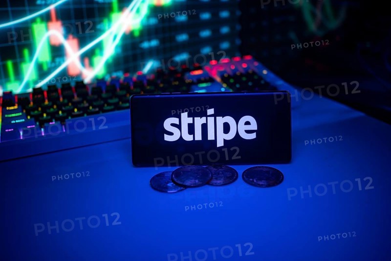 Stripe shown on a smartphone surrounded by coins and trading visuals