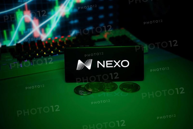 NEXO on a smartphone with currency tokens and fluctuating charts behind
