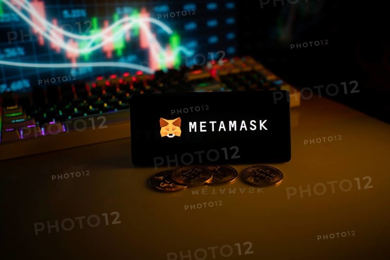 Phone features MetaMask logo with crypto coins and brightly lit trading screen