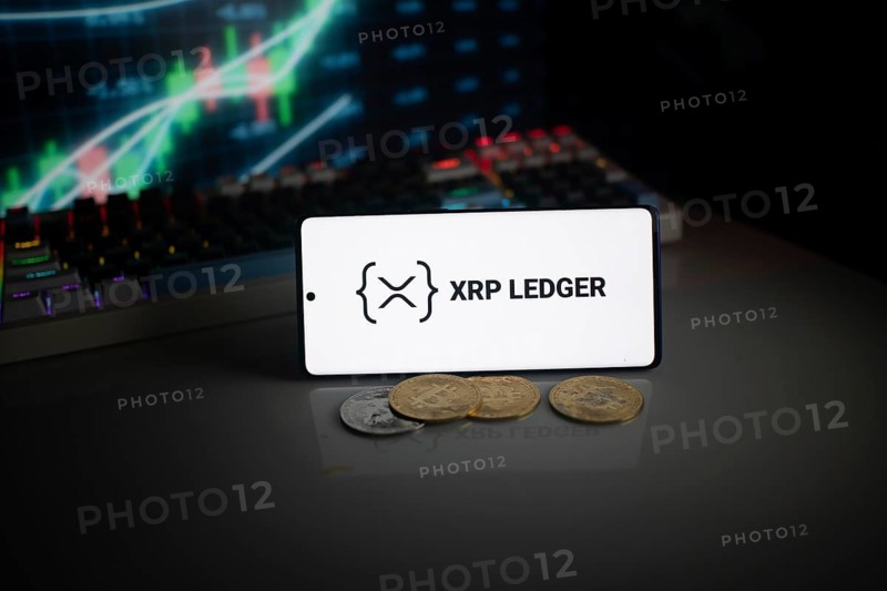 Phone displays XRP Ledger logo with crypto coins and trading graphics visible