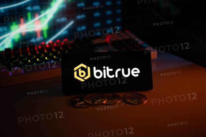 Bitrue logo in a dark setting with a glowing chart and coins, illuminated in orange