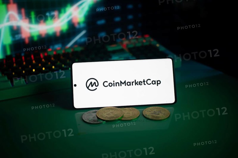 CoinMarketCap logo with coins and a glowing chart in a dim setting
