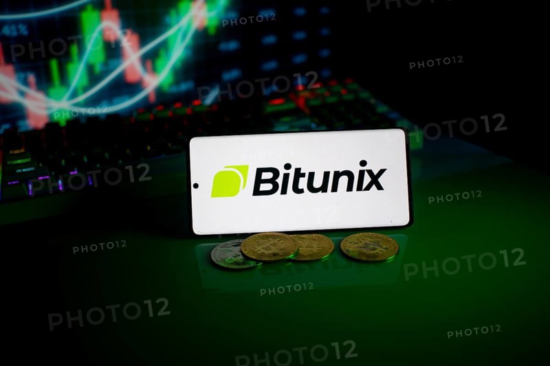 Bitunix logo on a phone with cryptocurrencies and market trend charts in the background