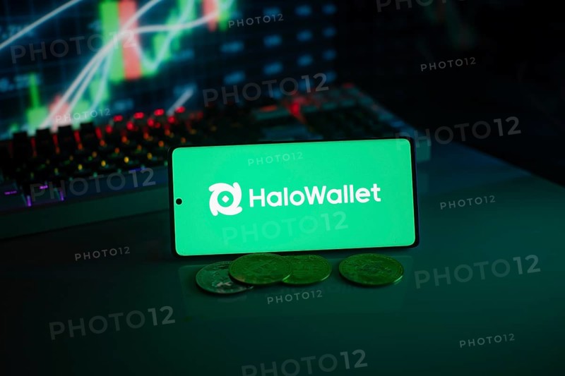 HaloWallet logo on smartphone with coins, green neon lights, and trading charts in background