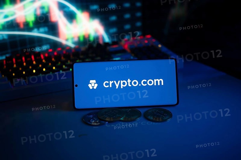 Crypto.com logo with coins and dynamic market graph in blue-lit setting