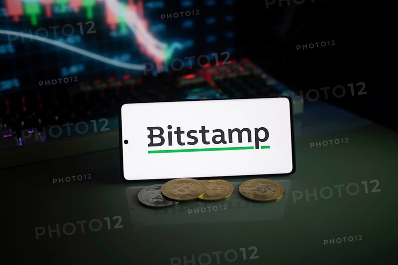 Bitstamp logo displayed with coins and market chart in electrifying neon lights