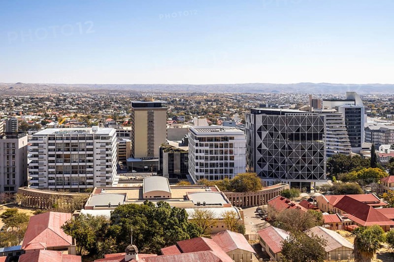 Modern downtown Windhoek, Namibia, with tall contemporary buildings, wide streets, moving cars, and a clear blue sky