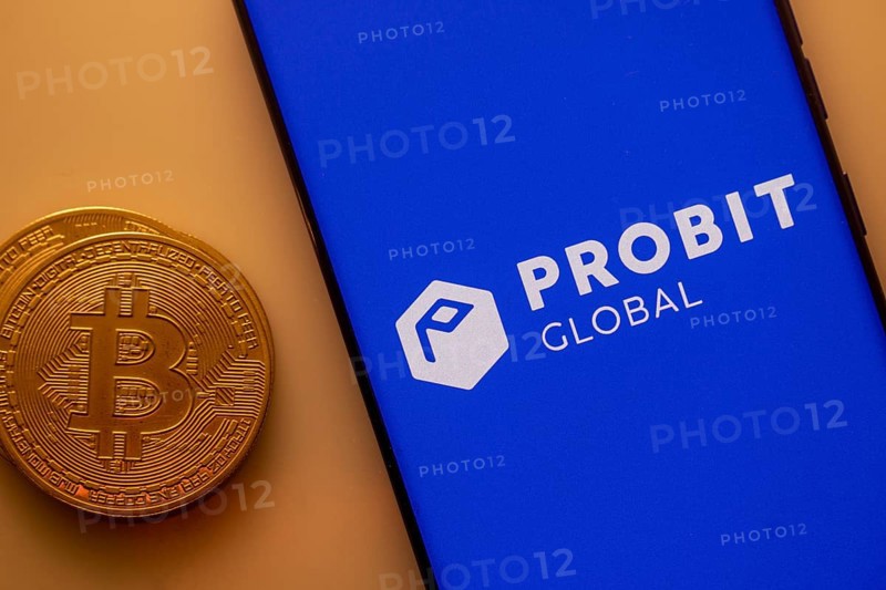 Bitcoin besides a smartphone displaying Probit Global app on blue background