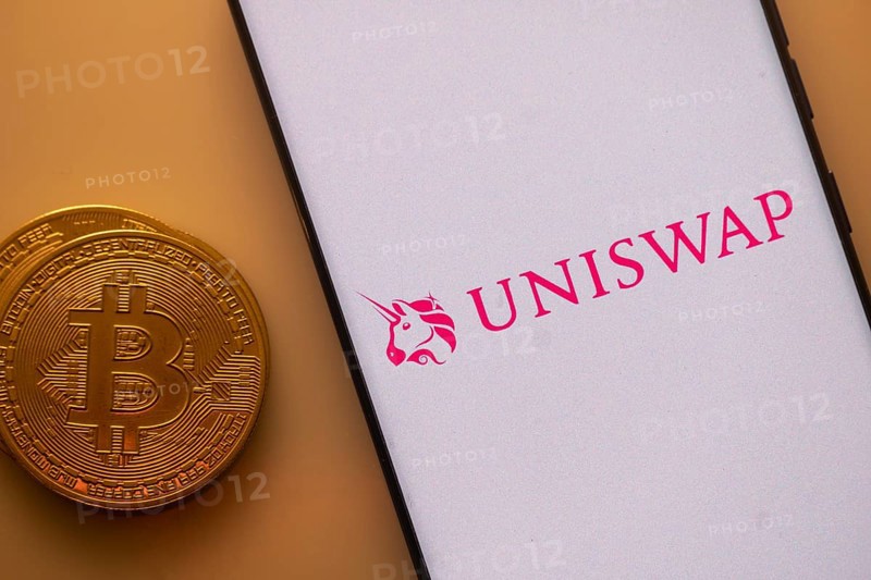 Uniswap app on a phone screen with a Bitcoin coin beside it
