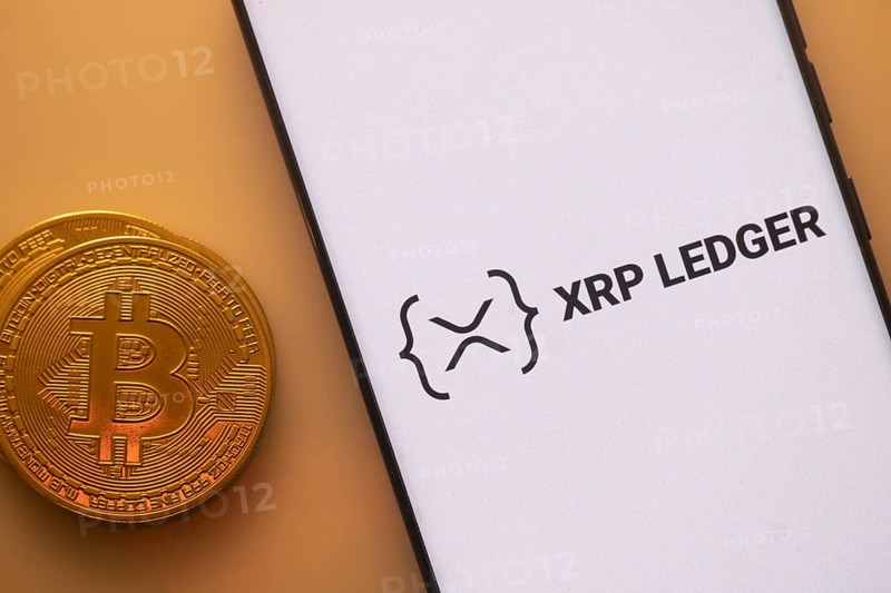 XRP Ledger logo on smartphone next to Bitcoin, emphasizing blockchain and cryptocurrency exchange