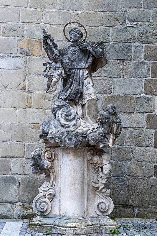 Stone statue of a saint on an ornate pedestal, baroque details in front of a stone wall, parish church St.Stephan Tulln Lower Austria Austria