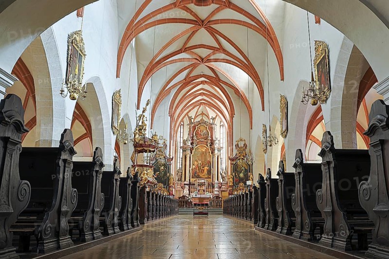 Symmetrical view of the church interior with ornate altar decorations and rows of pews, St. Stephen's parish church in Tulln, Lower Austria Austria