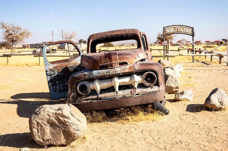 Solitaire's car graveyard in Namibia 27 August, 2025: features rusted vintage cars near small desert buildings, set against dunes and mountains, capturing desert charm and isolation