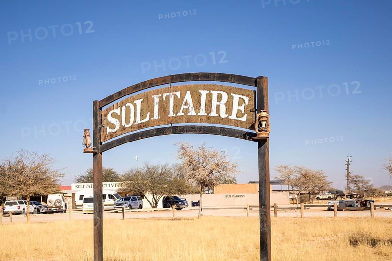The remote desert settlement of Solitaire in Namibia - 27 August, 2025: features a sign displaying the town's name, set against golden sand dunes and rugged mountains