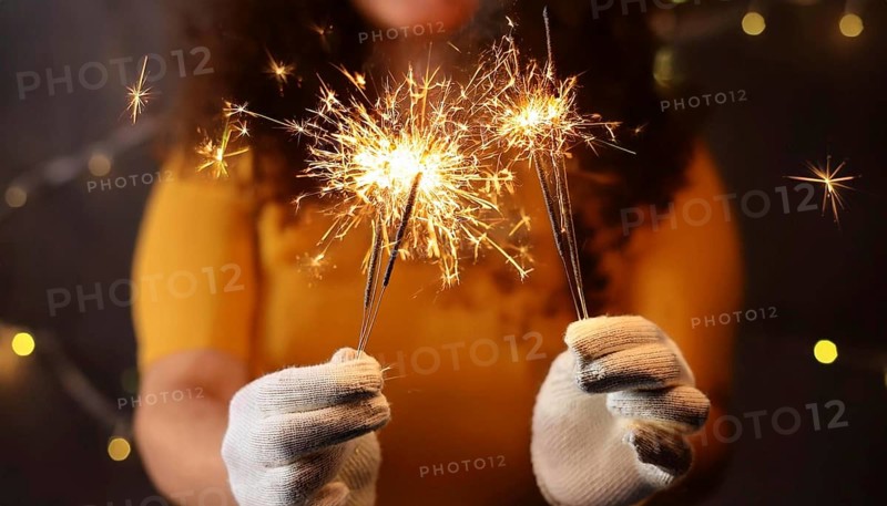 Woman wearing white gloves holding burning sparklers celebrating christmas eve, AI generated