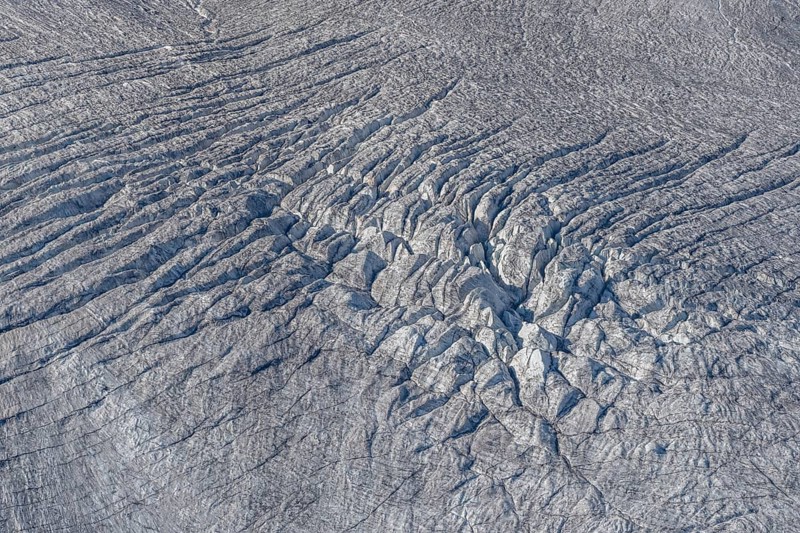 Crevasses and streaks mark the surface of the glacier. The sunlight highlights these unique geological formations. Overview of climate change in action. Gorner Glacier, Zermatt, Valais, Alps, Swiss