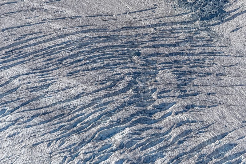 Crevices mark the surface of the glacier. The landscape is illuminated by daylight, highlighting the structure and colour of the ice. Gorner Glacier, Zermatt, Valais, Alps, Swiss