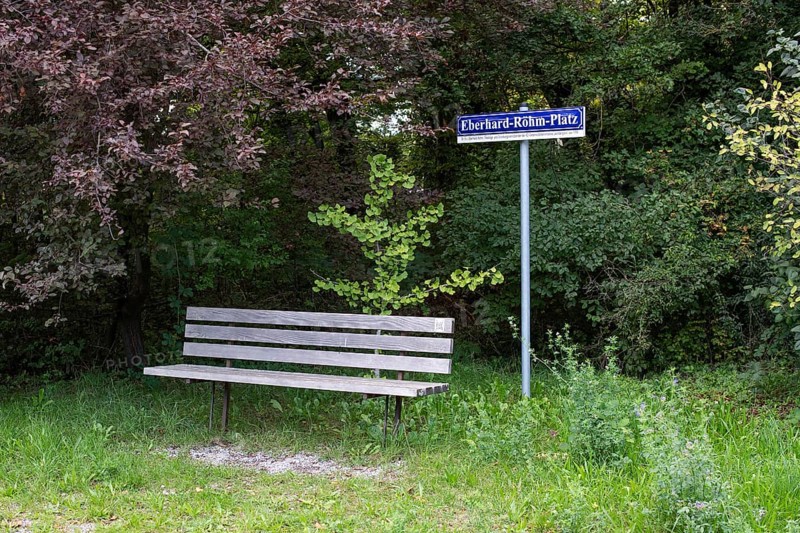 Wooden bench in front of a sign with the inscription Eberhard-Röhm-Platz, square named after a founding member of the Leonberg Concentration Camp Memorial, Leonberg, Baden-Württemberg