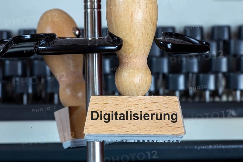 Stamp with added text DIGITALISATION in front of a typewriter