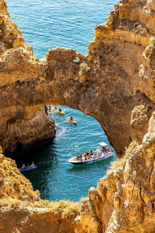 Crowds of excursion boats at the caves and rocky gates of the Ponta da Piedade rocky coast, rugged coastal landscape, right by the centre of Lagos, in the west of the Algarve, Portugal